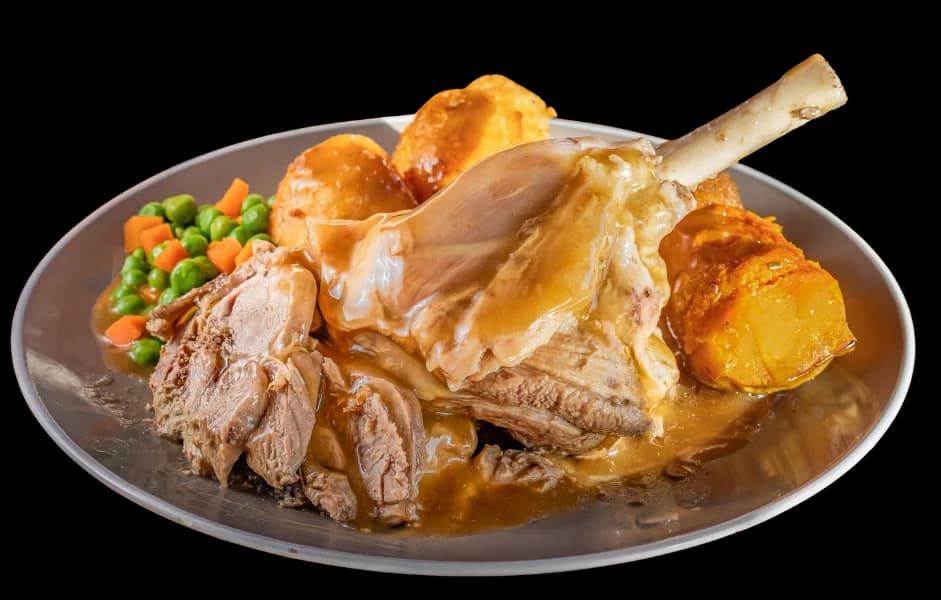 Slow-roasted lamb shank meal with roast potatoes, pumpkin, peas and carrots