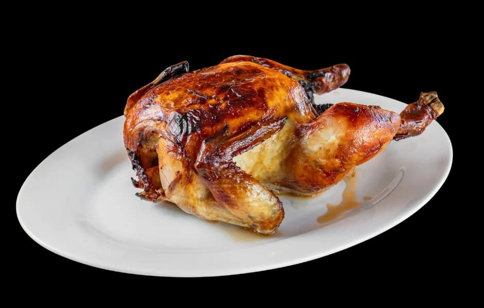 A golden whole roast chicken on a white plate