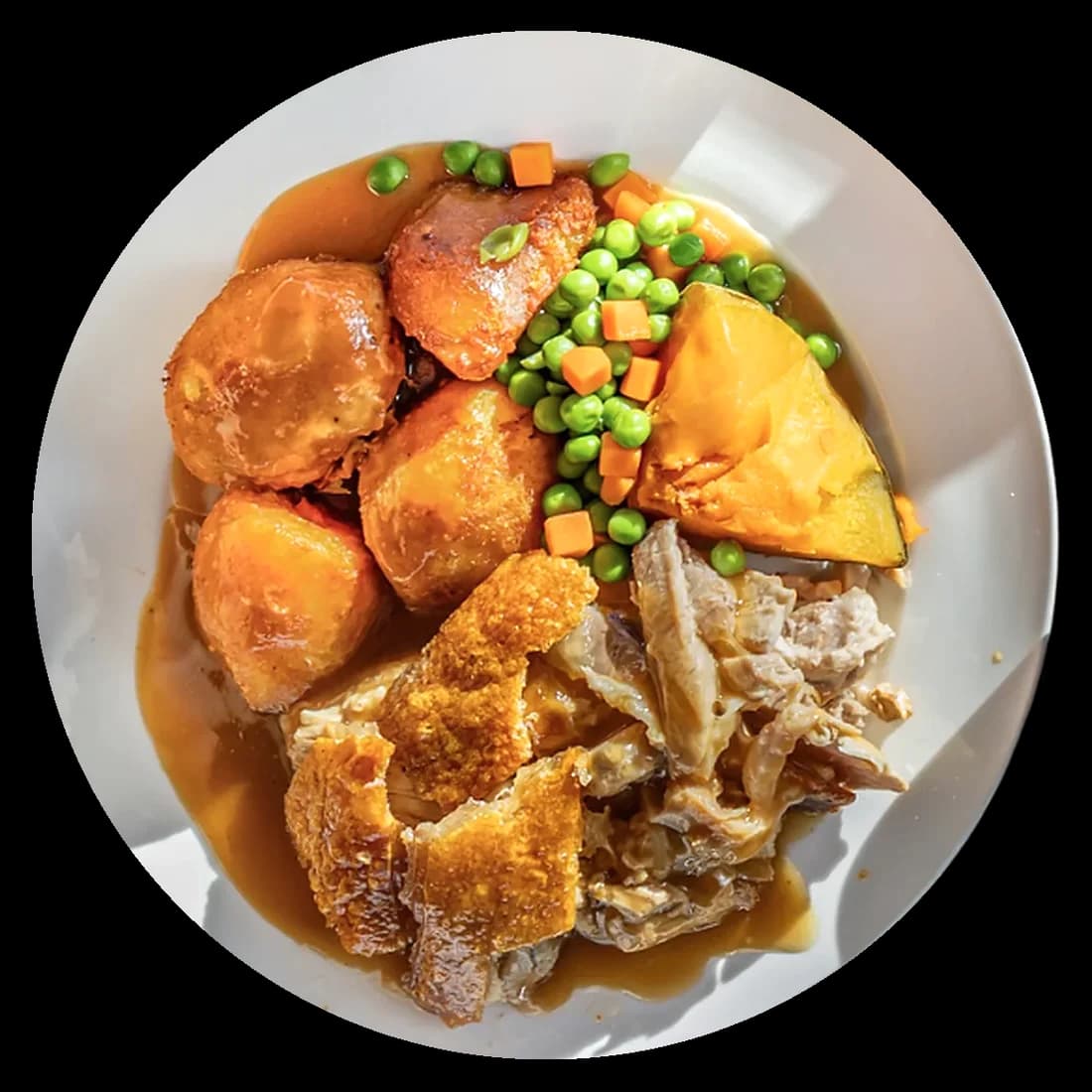 A Kaiapoi Roast pork roast from above: crackling, roast potatoes, pumpkin, peas and carrots under homemade gravy